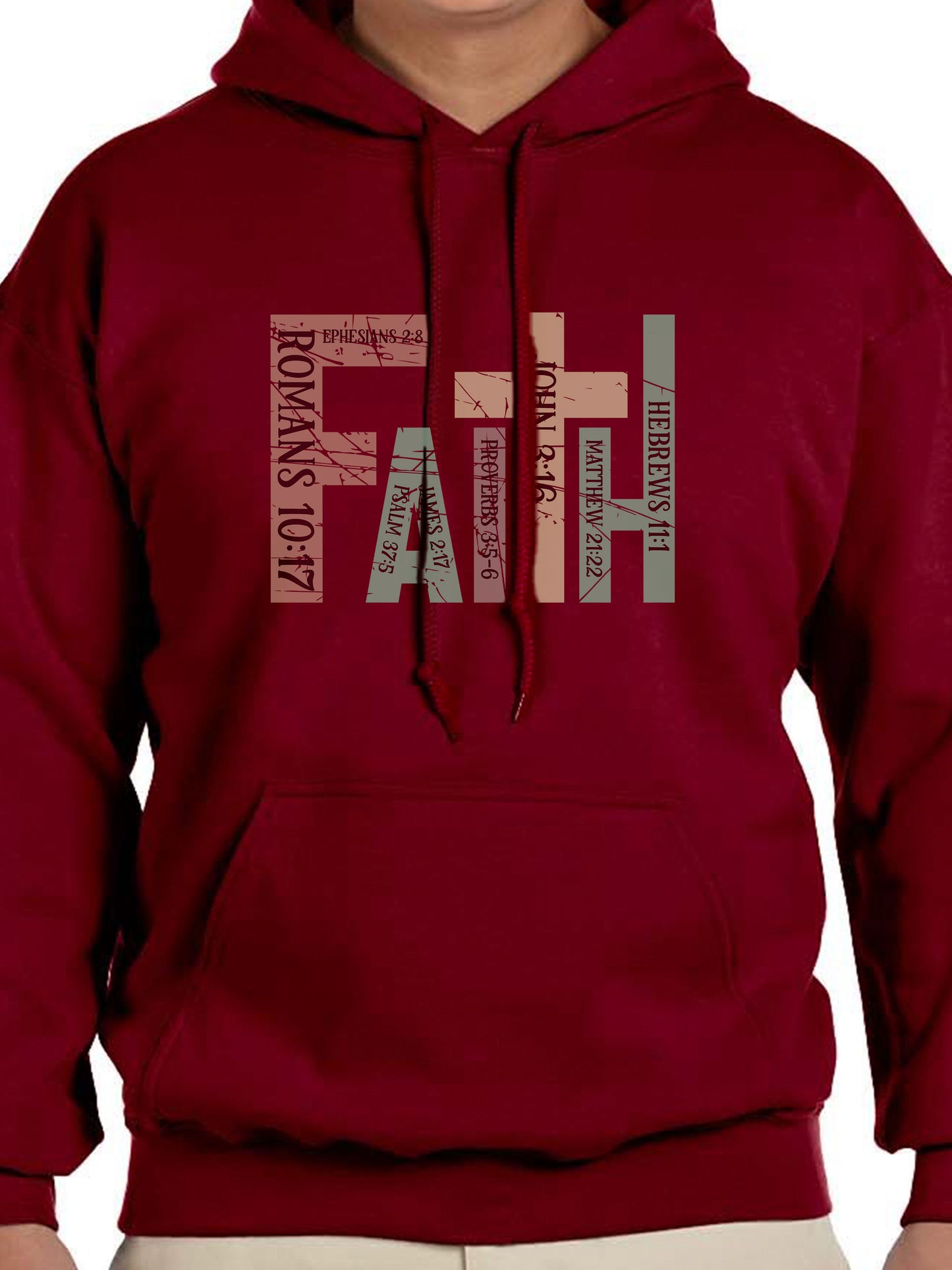 Man wearing a garnet hoodie with the word “FAITH” printed in block letters across the chest. Each letter is filled with a Bible verse reference, including Romans 10:17, Ephesians 2:8, Psalm 37:5, Proverbs 3:5–6, John 3:16, Matthew 21:22, and Hebrews 11:1. The design combines bold typography and scripture for a powerful, faith-centered statement.