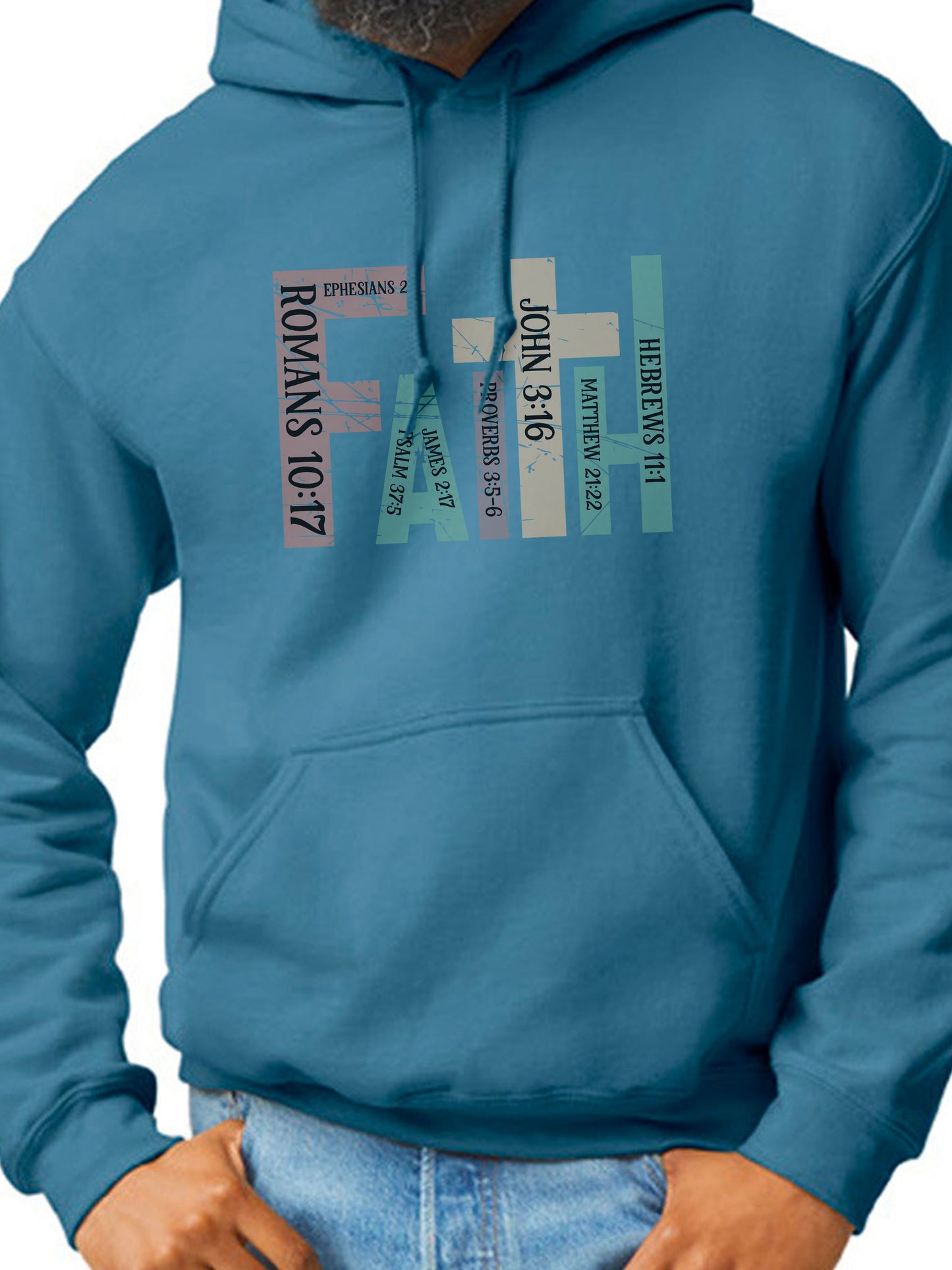 Man wearing a INDIGO BLUE hoodie with the word “FAITH” printed in block letters across the chest. Each letter is filled with a Bible verse reference, including Romans 10:17, Ephesians 2:8, Psalm 37:5, Proverbs 3:5–6, John 3:16, Matthew 21:22, and Hebrews 11:1. The design combines bold typography and scripture for a powerful, faith-centered statement.