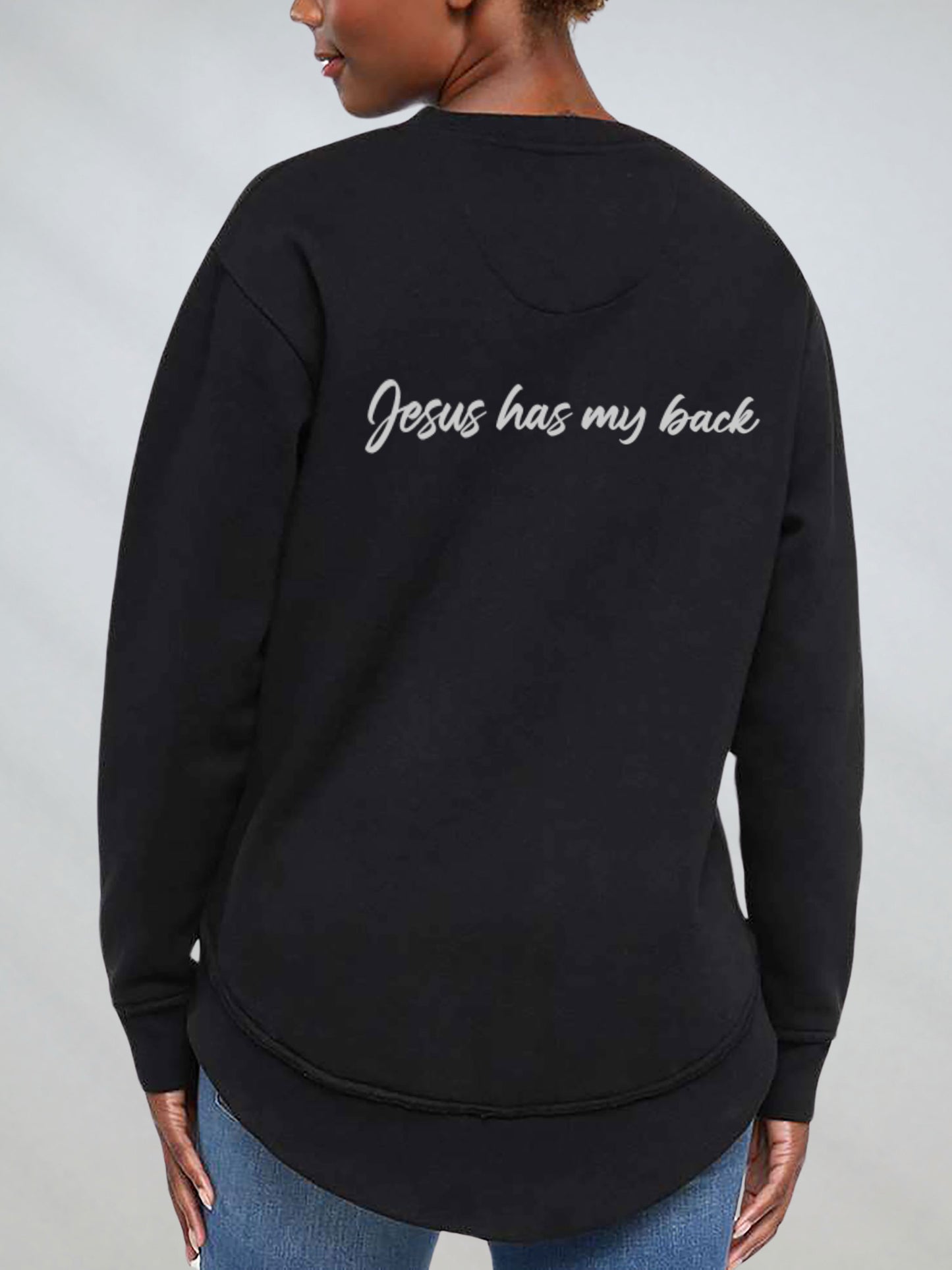 Black sweatshirt with 'Jesus has my back' text on the back, worn by a person against a plain background.