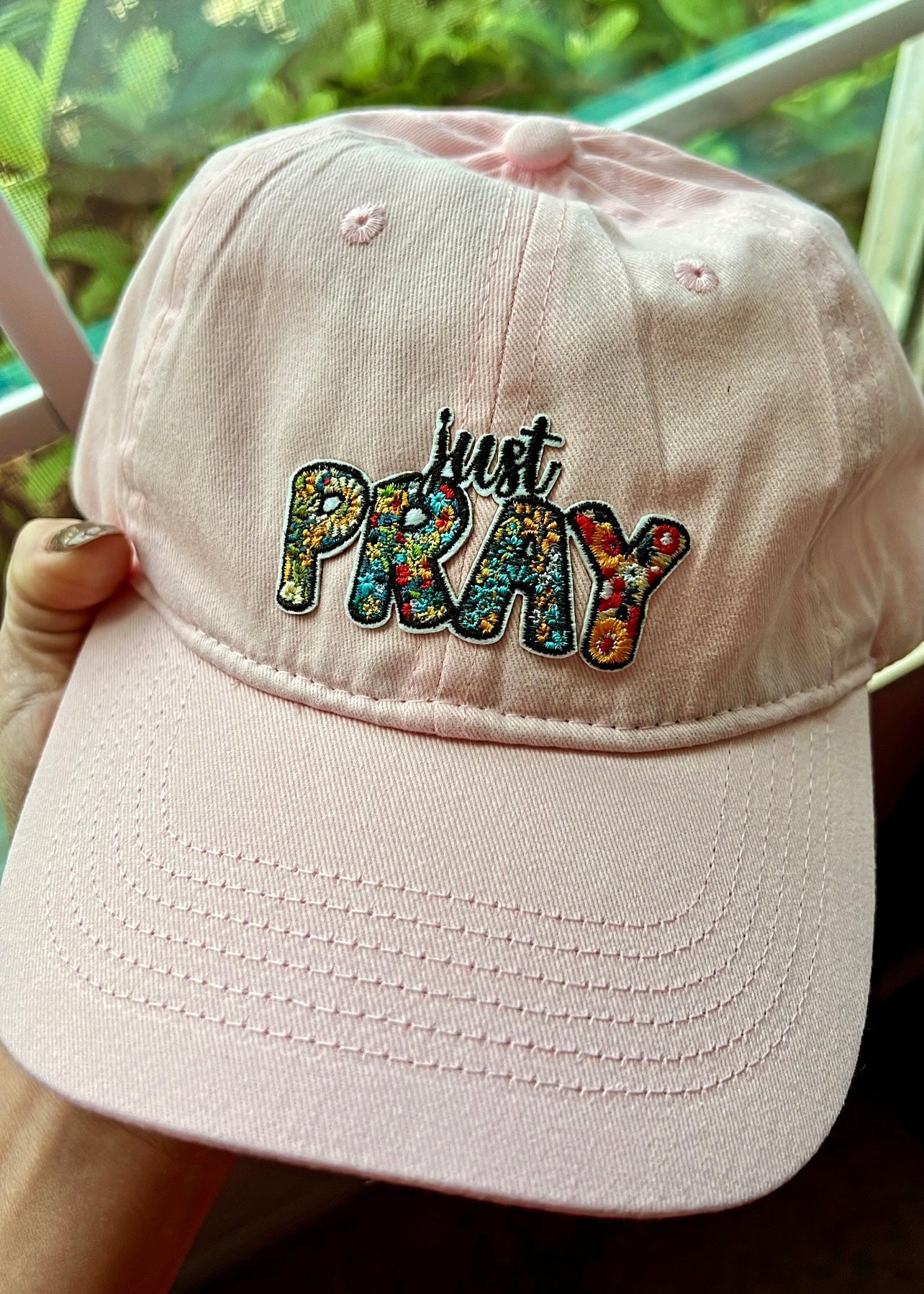 Blush pink baseball cap with “Just Pray” embroidered floral patch on the front.