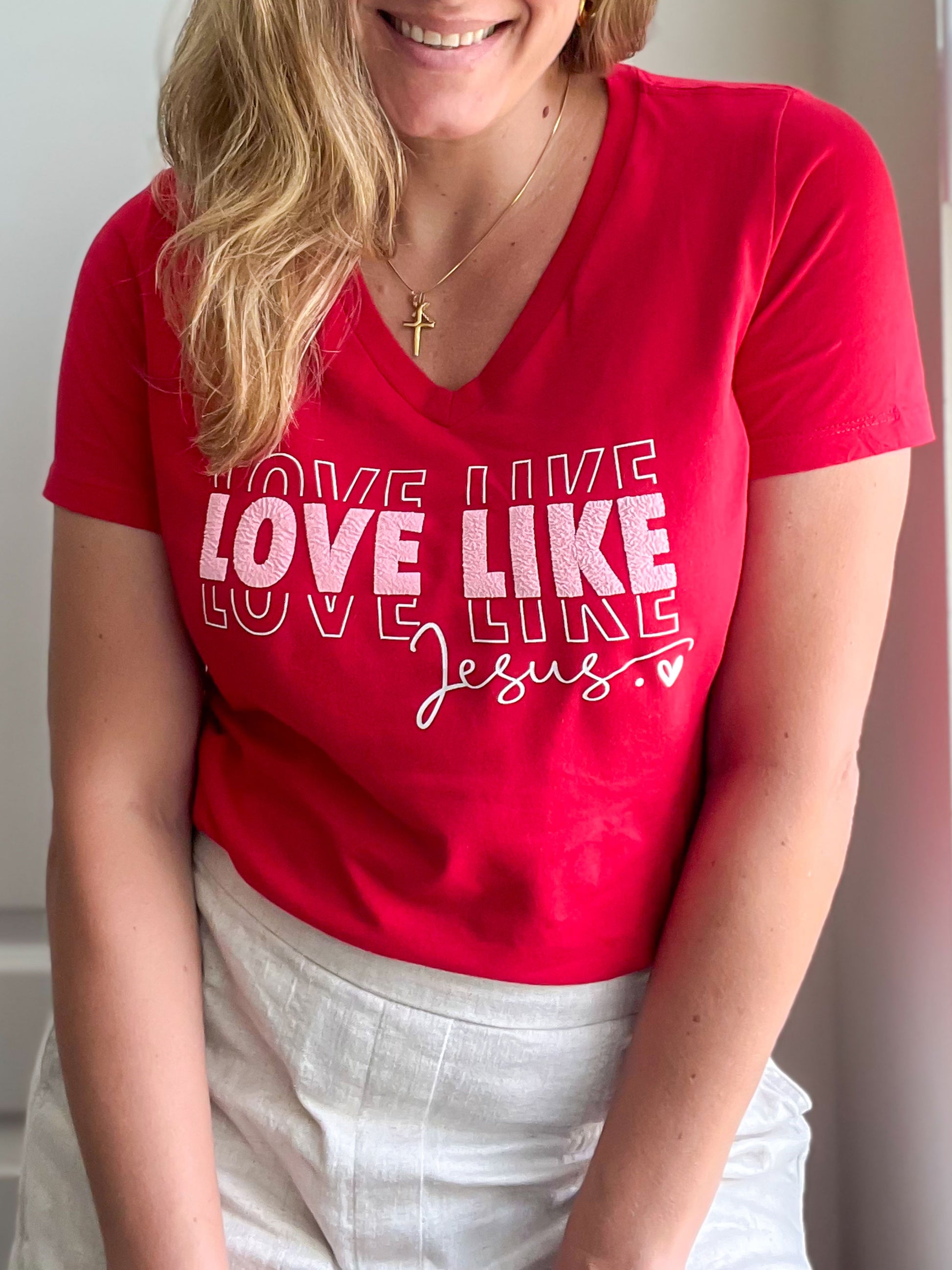 Front view of red “Love Like Jesus” v-neck t-shirt featuring bold puff print text.