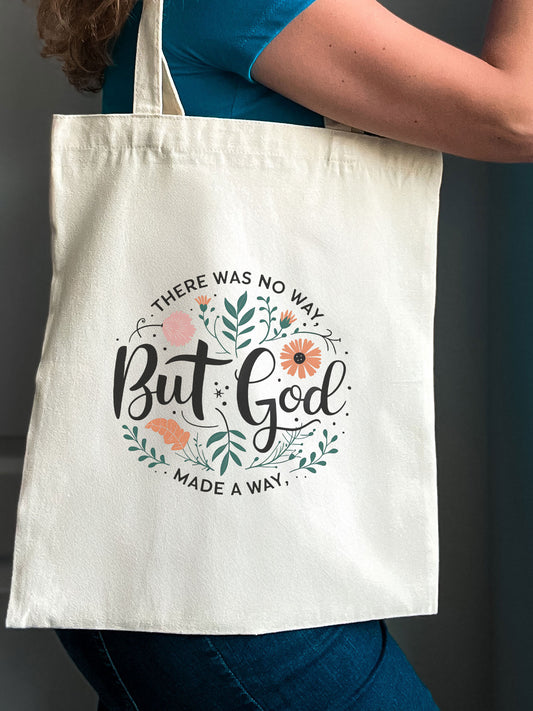 Woman holding a Christian tote bag with floral design and the phrase “There was no way, but God made a way.”