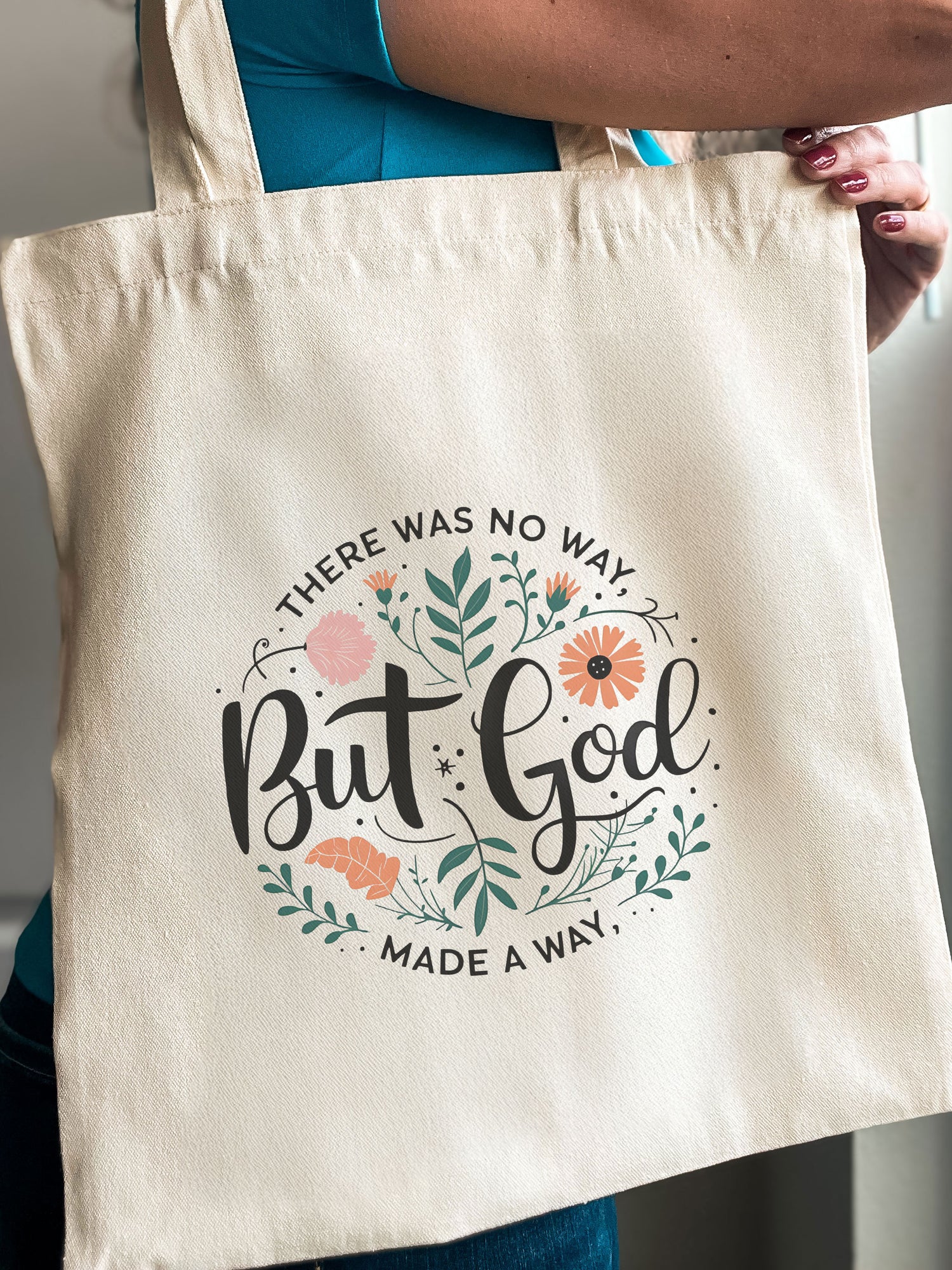 Woman holding a Christian tote bag with floral design and the phrase “There was no way, but God made a way.”