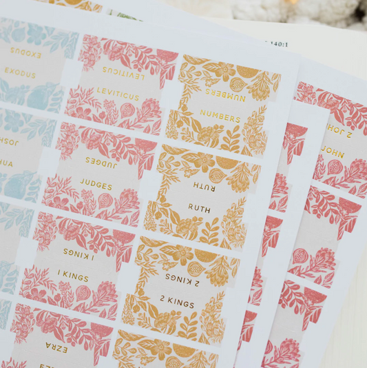 Close-up of colorful citrus floral Bible tabs with gold lettering, showing books like Numbers and Ruth.