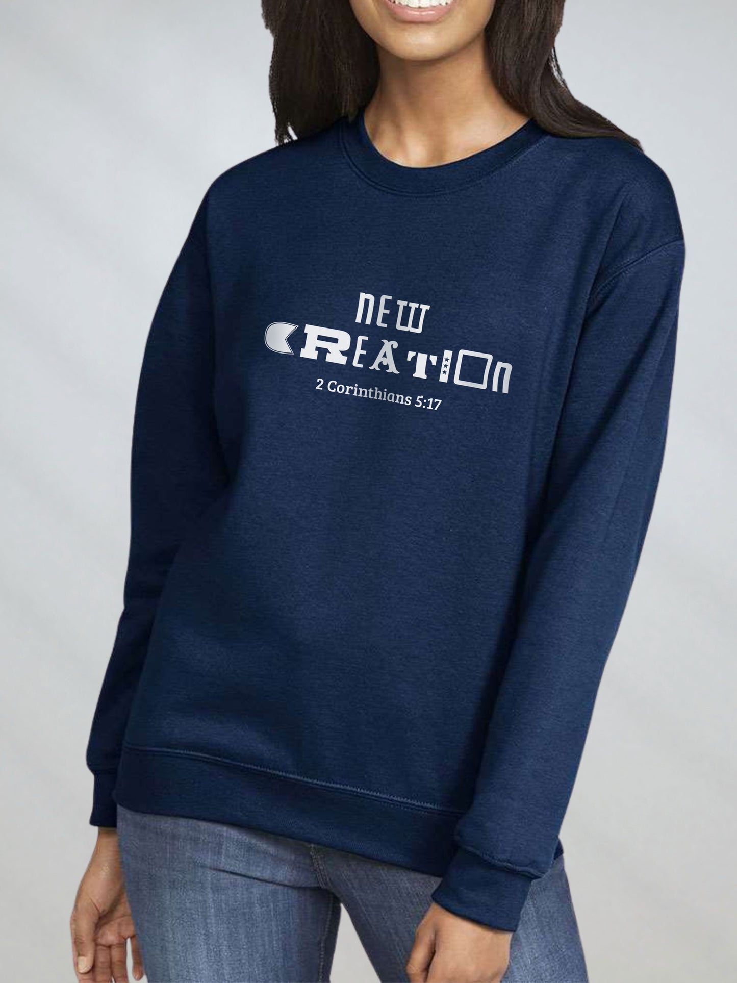 Woman wearing navy sweatshirt with “New Creation – 2 Corinthians 5:17” design