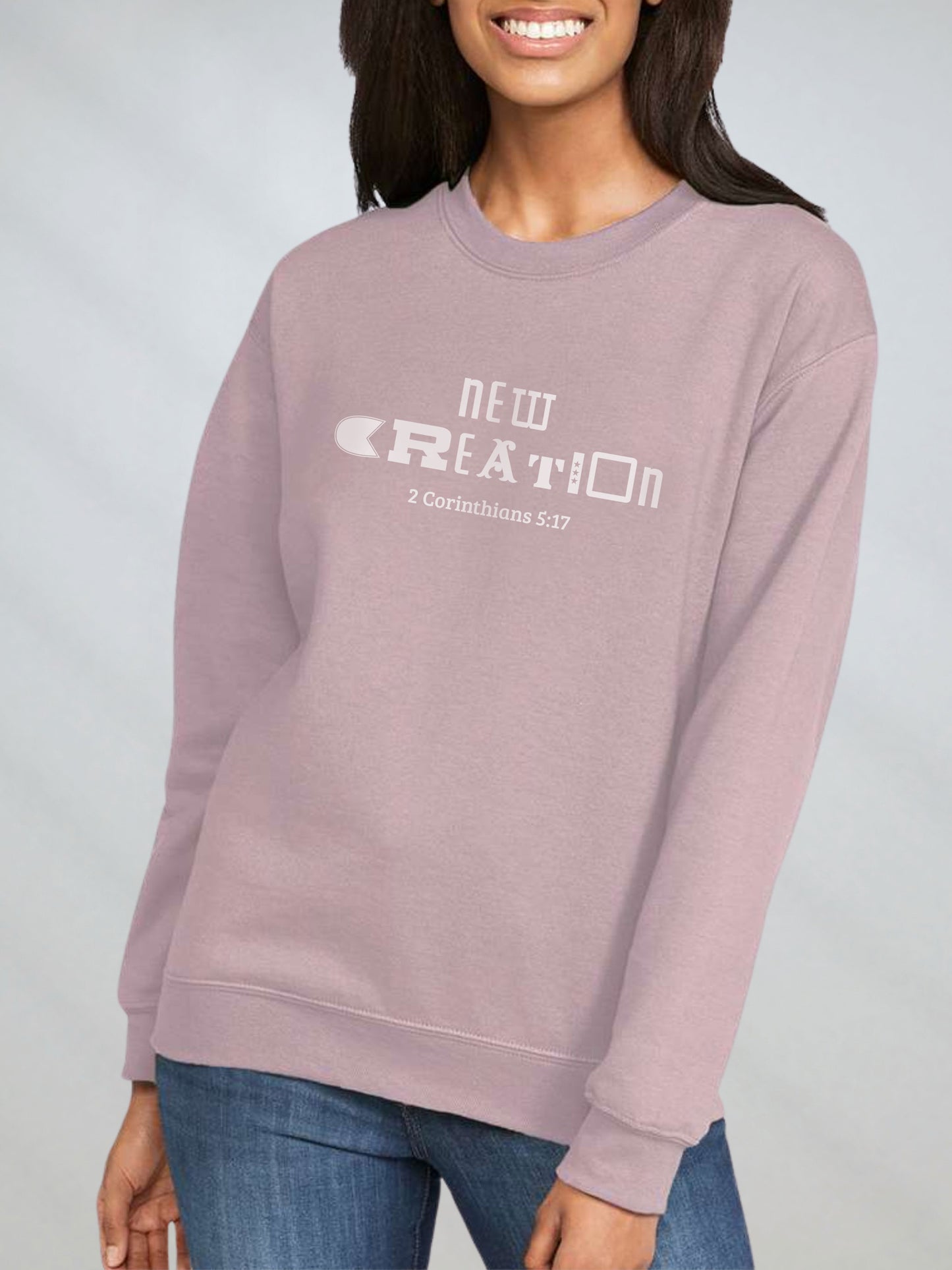 Woman wearing paragon-color sweatshirt that says “New Creation – 2 Corinthians 5:17”