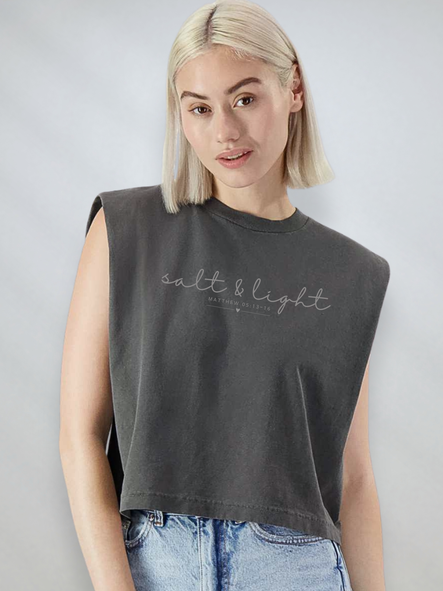Women’s faded black heavyweight muscle tee featuring the phrase “Salt & Light” and Matthew 5:13–16 in a minimalist script design.