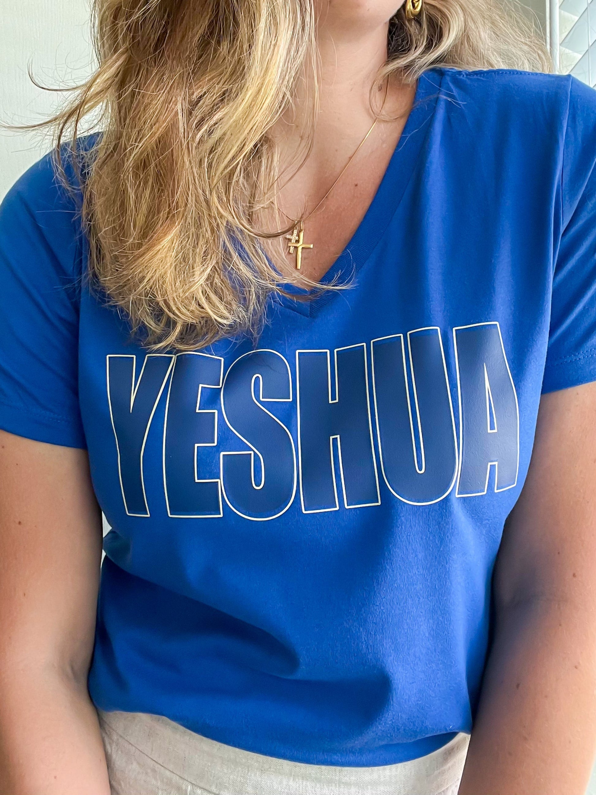 Close-up of blue V-neck Yeshua t-shirt with bold white outline design