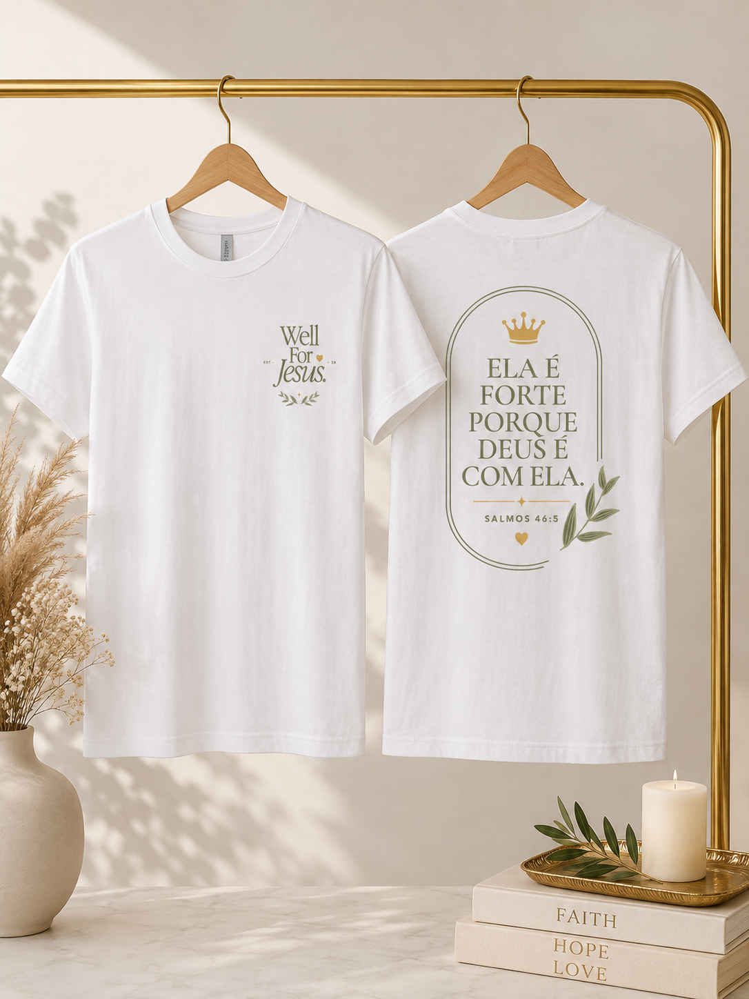Two white short-sleeve T-shirts hanging on a gold clothing rack, shown front and back. The front shirt has a small gold chest print reading 'Well For Jesus,' and the back shirt has a large oval gold print with Portuguese text, a small crown, and olive branch details.