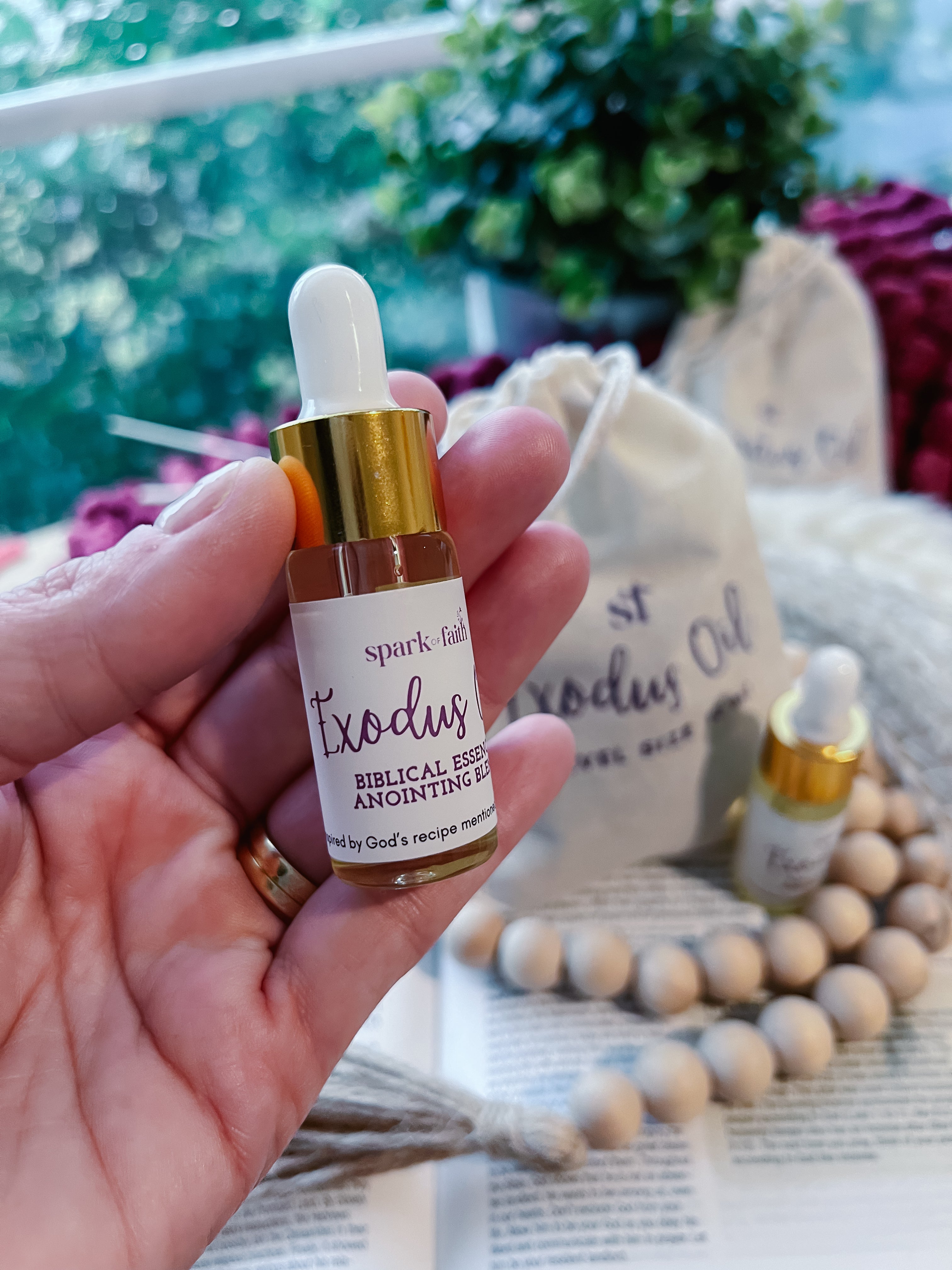 A hand holding a 10 ml bottle of the Exodus Anointing Oil, a travel size option available.