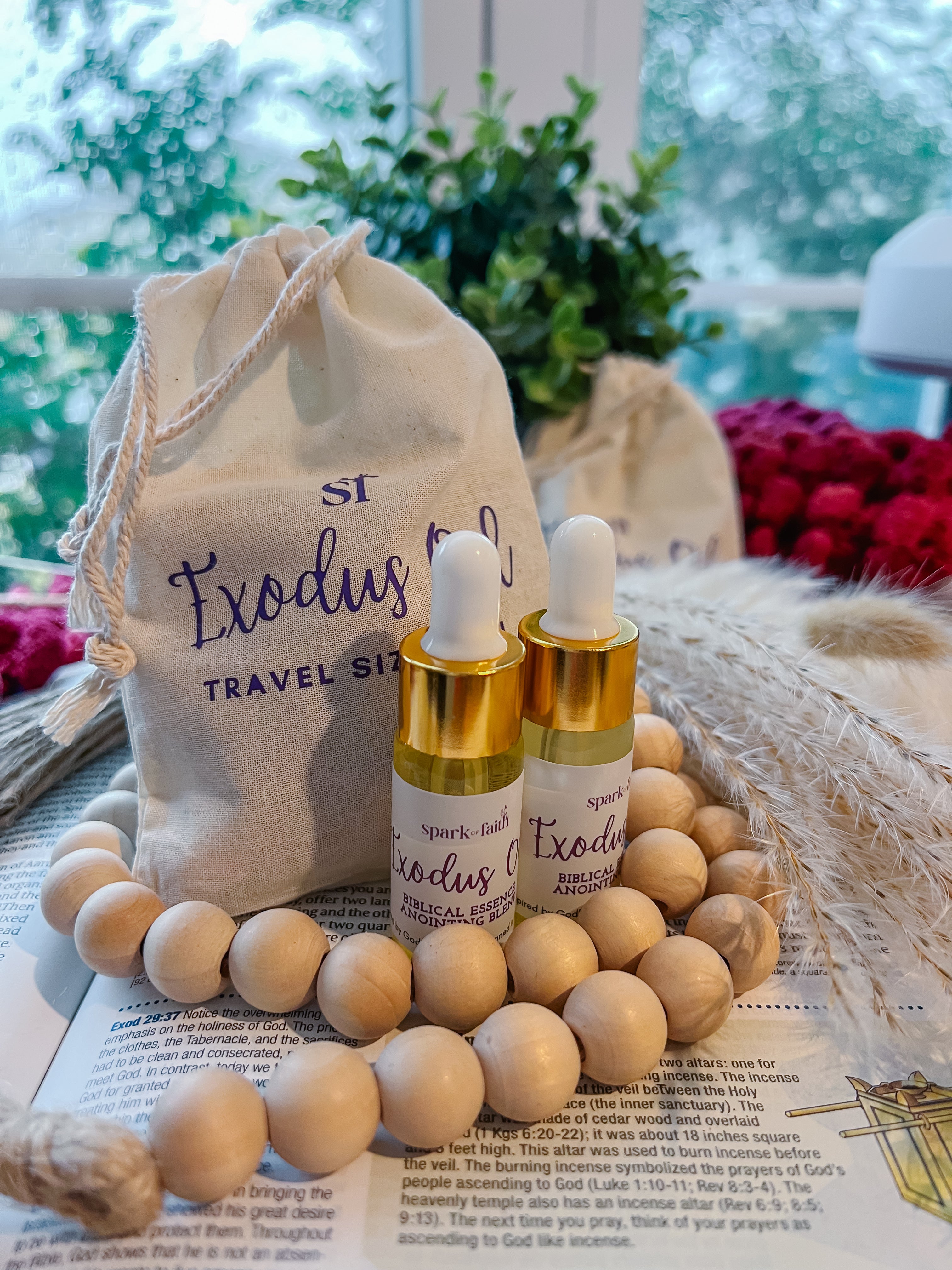 2 bottles of the Exodus Anointing Oil travel size (10 ml) on the top of a Bible, with the bag/ packaging behind it, in a cozy environment.