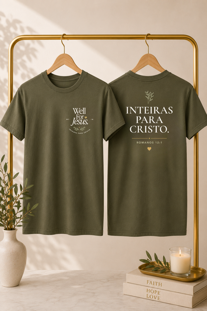 Two olive green graphic T-shirts hanging on a gold clothing rack, showing the front and back designs. The front reads 'Well For Jesus' with decorative text, and the back reads 'INTEIRAS PARA CRISTO' with a small heart and floral detail.