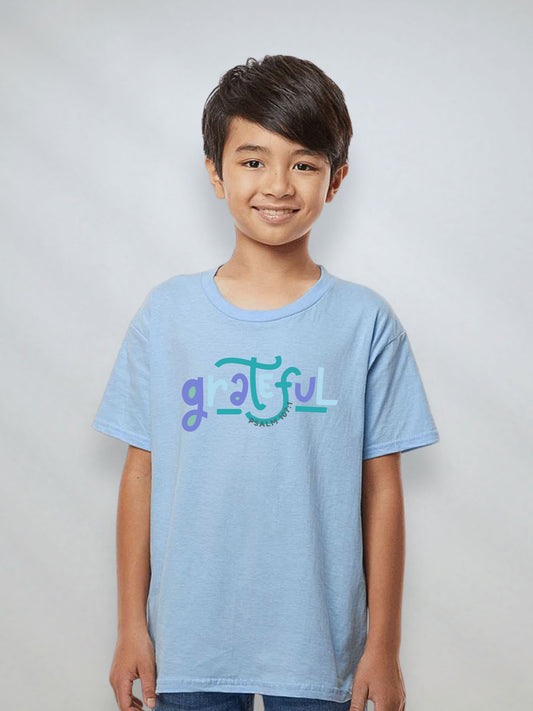 Youth boy wearing a light blue Christian t-shirt with the word “Grateful” and Psalm 107:1.