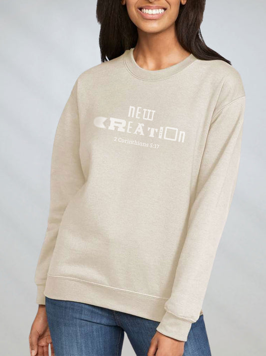 Woman in sand-colored sweatshirt with “New Creation – 2 Corinthians 5:17” design