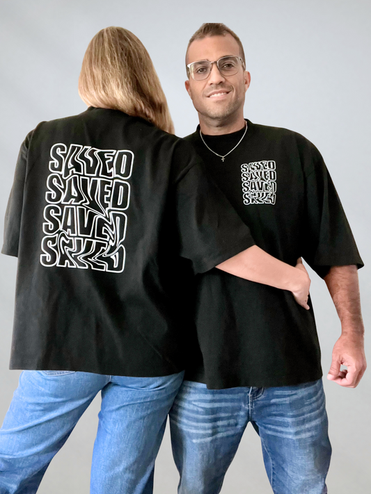 Two people wearing matching black t-shirts with 'SAVED' text design on a plain background